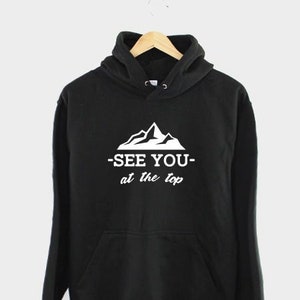 May include: Black hoodie with a white mountain graphic and the text "See you at the top" printed on the front.