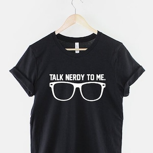May include: Black t-shirt with white text that reads "Talk Nerdy To Me."  The text is above a pair of white eyeglasses.