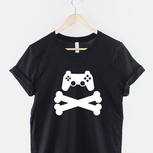 May include: Black t-shirt with a white graphic of a video game controller and crossed bones.