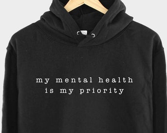 May include: Black hooded sweatshirt with the text "my mental health is my priority" printed in white on the front.