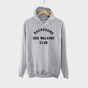 May include: A gray hooded sweatshirt with the text "Dachshund Dog Walking Club" printed on the front.