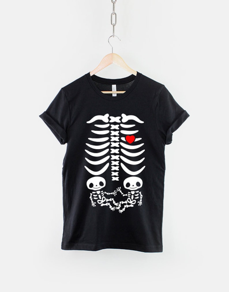 May include: Black t-shirt with a white skeleton graphic. The skeleton has a red heart in the chest area and two smaller skeletons in the stomach area.