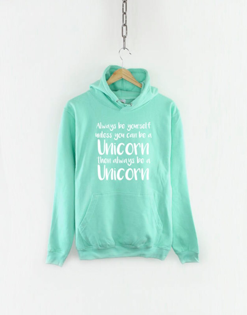 May include: A turquoise blue hooded sweatshirt with a white graphic print that reads "Always be yourself unless you can be a Unicorn then always be a Unicorn".