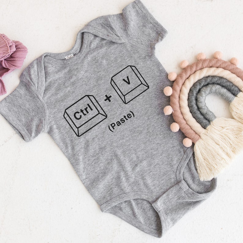 May include: A gray baby onesie with a black graphic of computer keys that reads "Ctrl + V (Paste)".