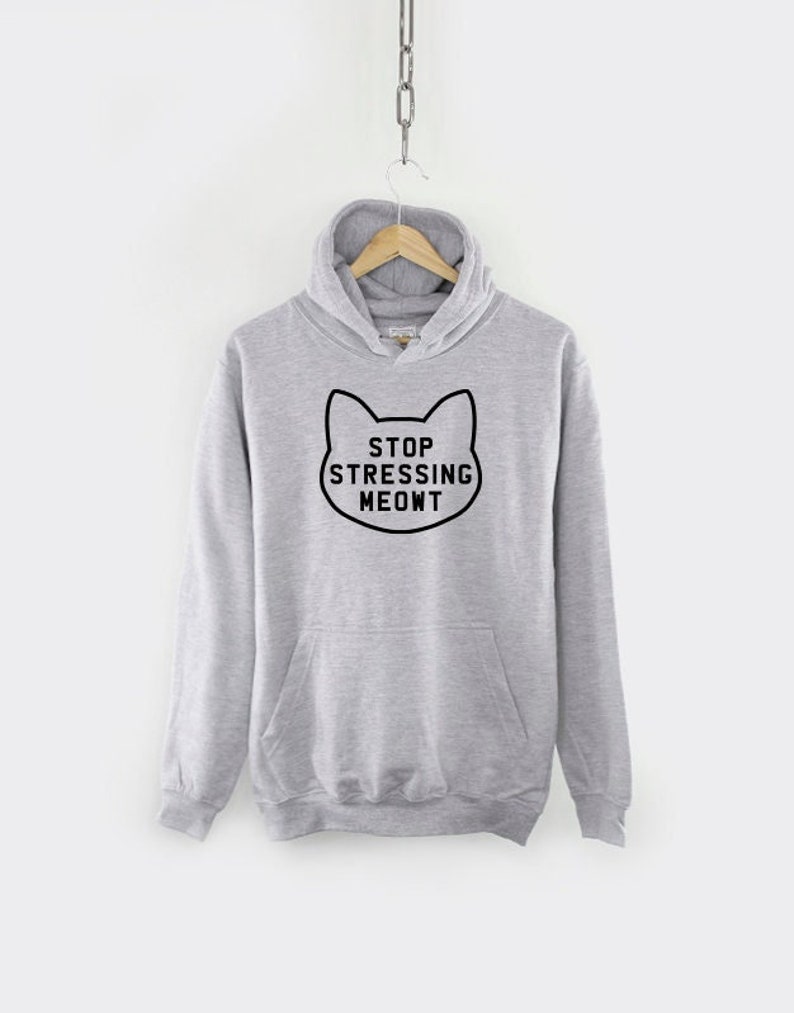 K&ouml;nnte beinhalten: Ein grauer Kapuzenpullover mit einem schwarzen Katzenmotiv und dem Text "STOP STRESSING MEOWT".