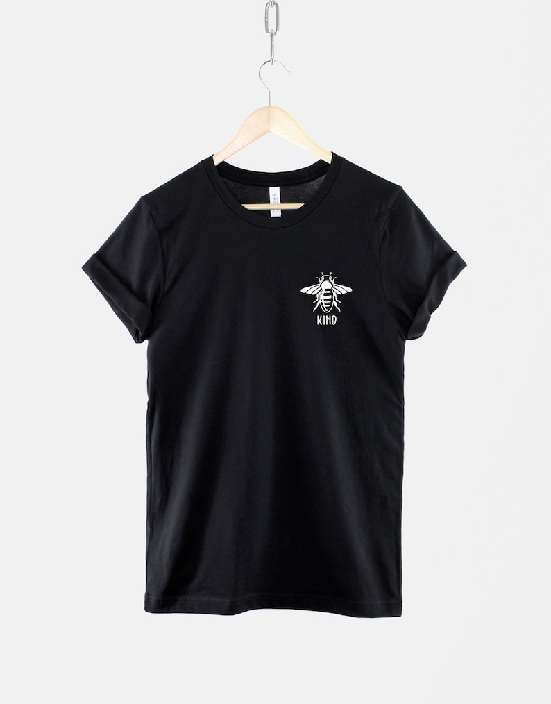 Op de afbeelding: Zwart T-shirt met een witte bij-afbeelding en het woord "KIND" eronder.