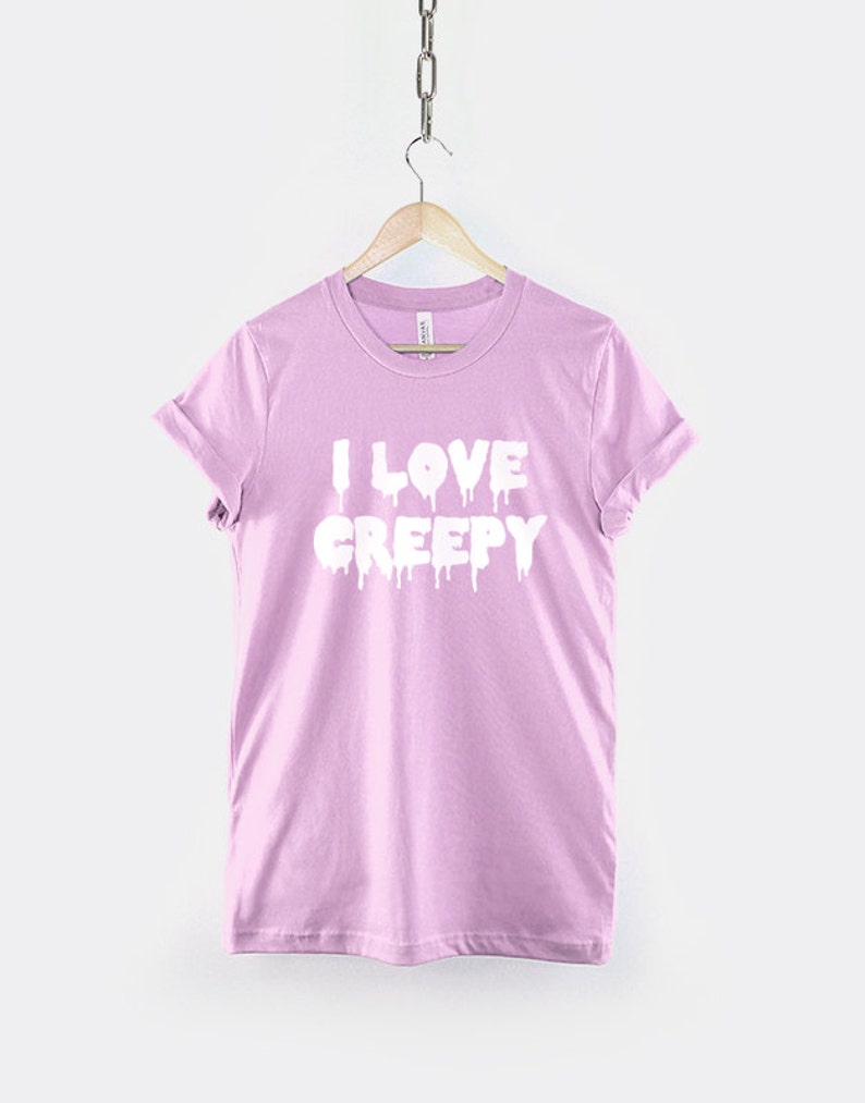 Puede incluir: Una camiseta rosa claro con el texto "I LOVE CREEPY" en letras blancas que gotean.