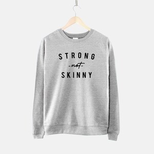May include: Gray sweatshirt with the text "STRONG -not- SKINNY" printed on the front.
