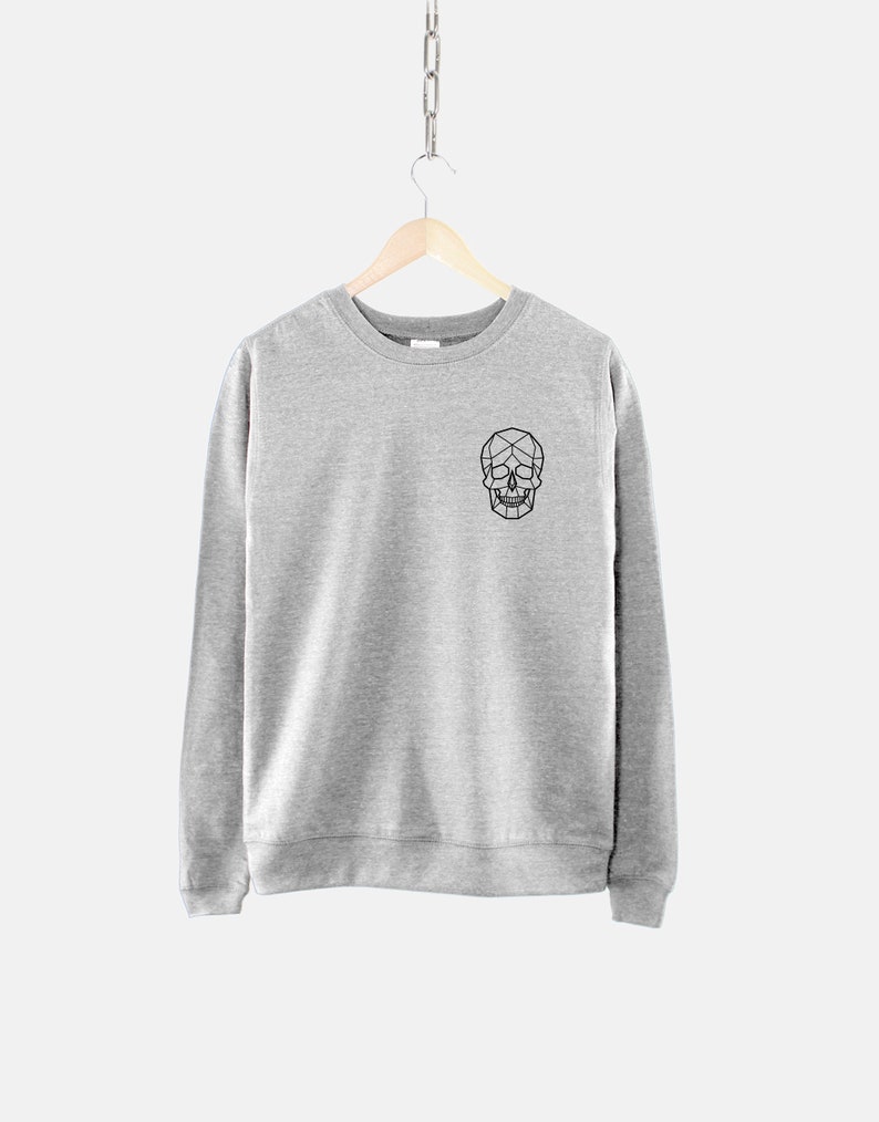 Puede incluir: Una sudadera gris con un dise&ntilde;o de calavera geom&eacute;trica negra en la parte delantera.