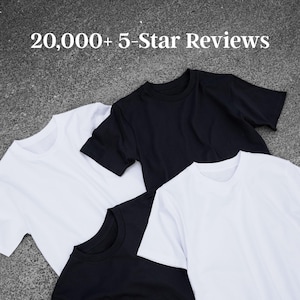 a collection of three t-shirts, one white, one black, and one solid black, laid out on a gray surface.