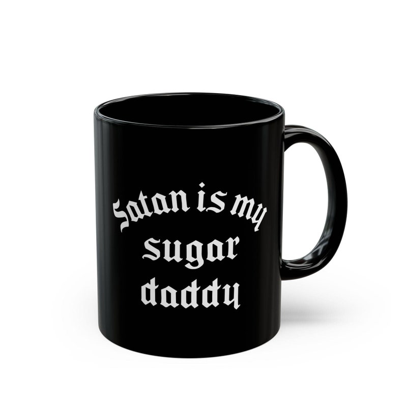 Puede incluir: Taza de caf&eacute; de cer&aacute;mica negra con texto blanco que dice "Satan is my sugar daddy".