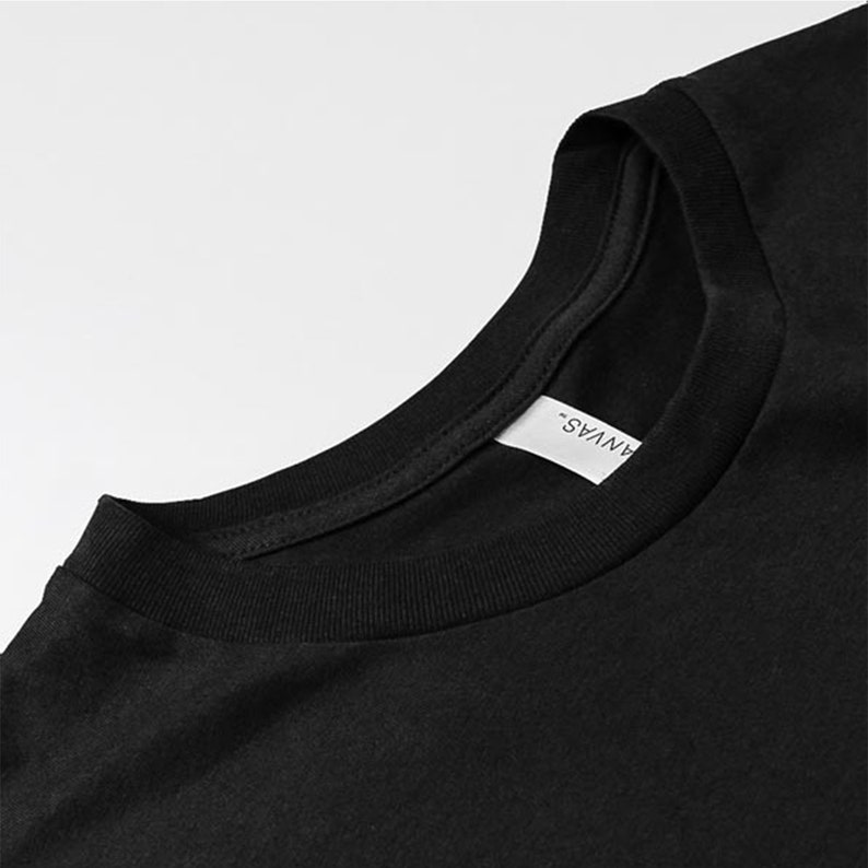 Puede incluir: Primer plano del cuello de una camiseta negra con una etiqueta blanca que dice "ANVAS".