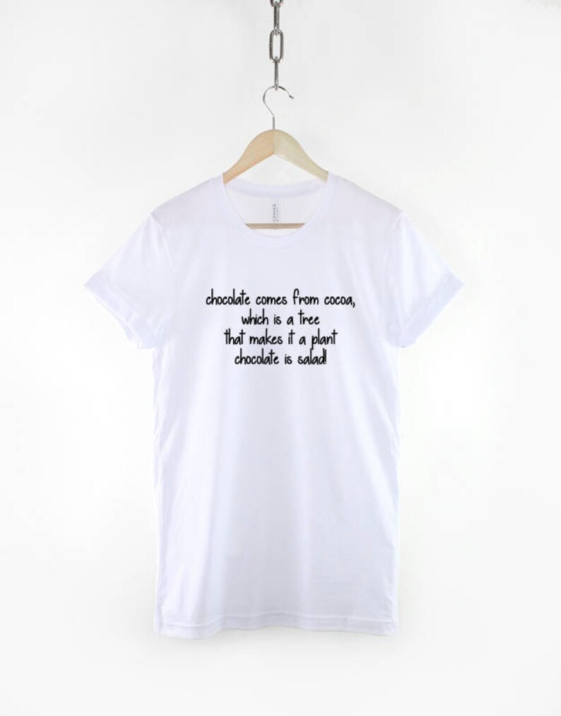 May include: White t-shirt with black text that reads "chocolate comes from cocoa, which is a tree that makes it a plant chocolate is salad!"