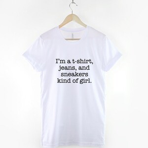 May include: White t-shirt with black text that reads "I'm a t-shirt, jeans, and sneakers kind of girl."