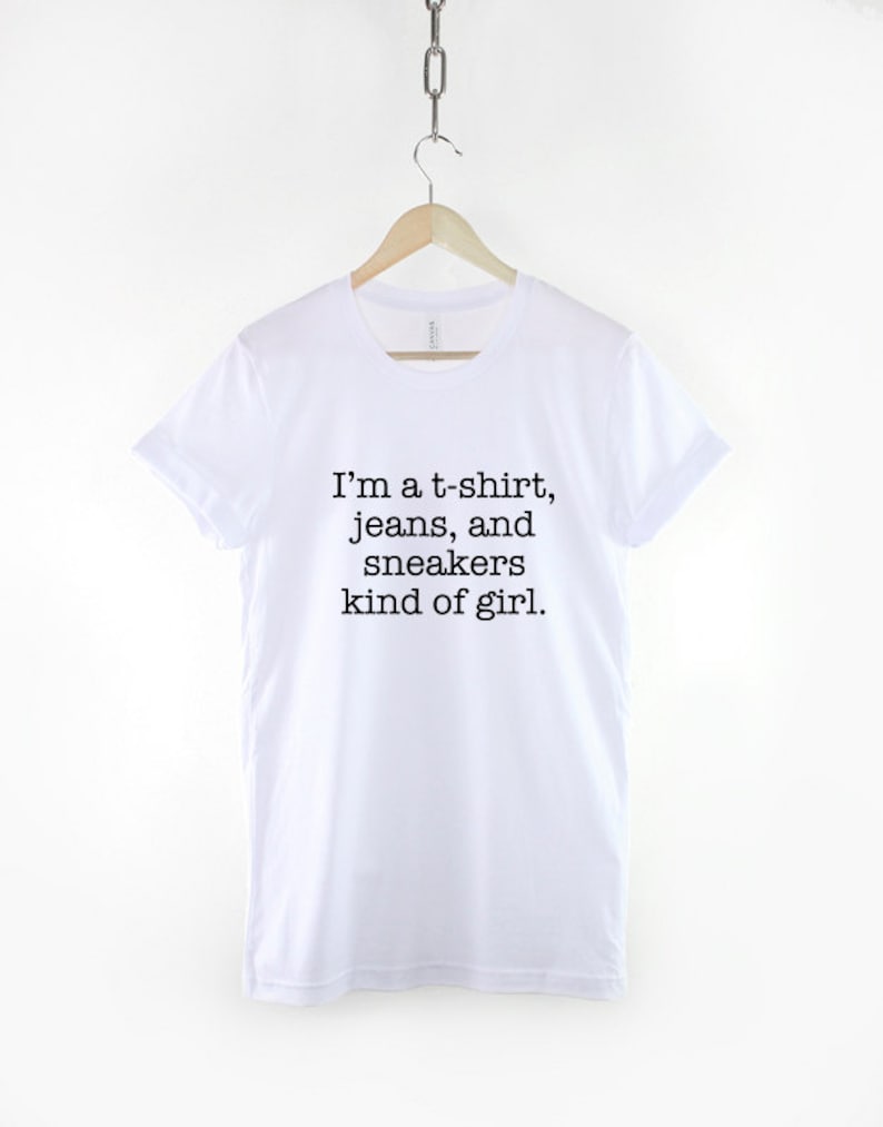 May include: White t-shirt with black text that reads "I'm a t-shirt, jeans, and sneakers kind of girl."
