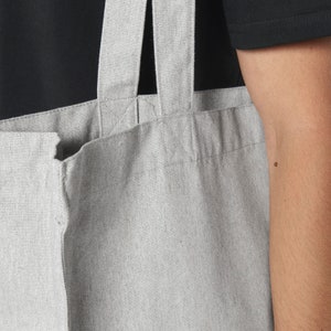 Puede incluir: Una bolsa de lona gris con dos asas gruesas. La bolsa est&aacute; hecha de una tela texturizada y tiene un dise&ntilde;o simple.