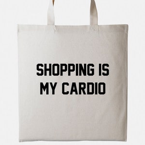 May include: A white canvas tote bag with black text that reads "SHOPPING IS MY CARDIO".
