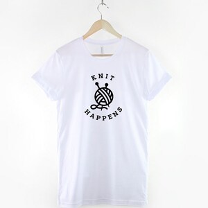 May include: White t-shirt with a black graphic of a ball of yarn with knitting needles and the text "Knit Happens".