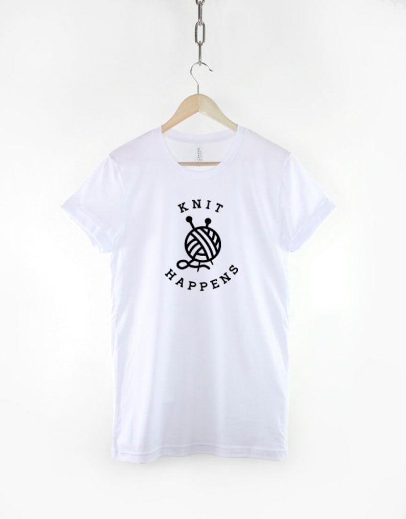 May include: White t-shirt with a black graphic of a ball of yarn with knitting needles and the text "Knit Happens".