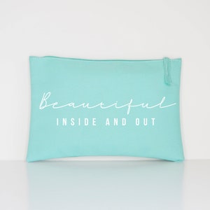 May include: A light blue zippered pouch with the text "Beautiful Inside and Out" in white.