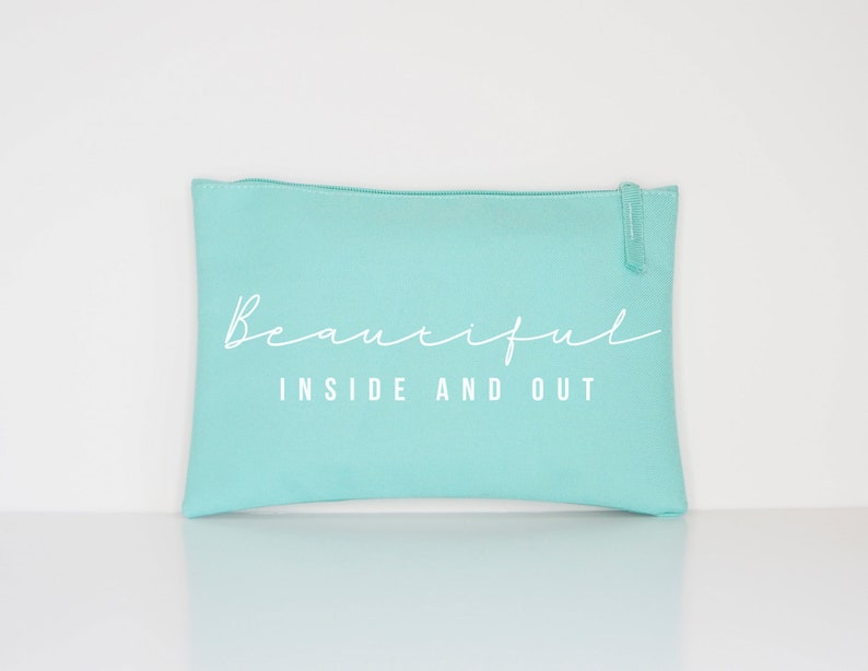 May include: A light blue zippered pouch with the text "Beautiful Inside and Out" in white.