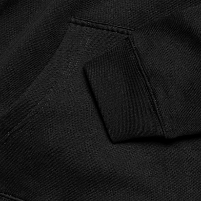 A close-up view of a black hoodie, showing the fabric and details of the garment.