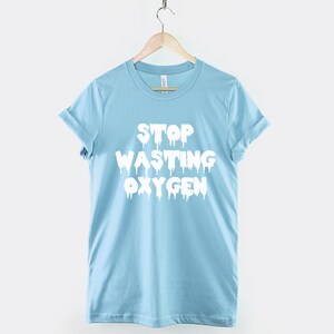 May include: A light blue t-shirt with the text "STOP WASTING OXYGEN" in white dripping letters.