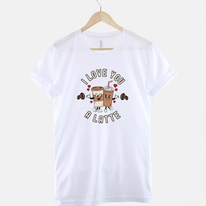 K&ouml;nnte beinhalten: Wei&szlig;es T-Shirt mit einem Motiv von zwei Kaffeetassen, die Hanteln halten, und dem Text "I love you a latte".