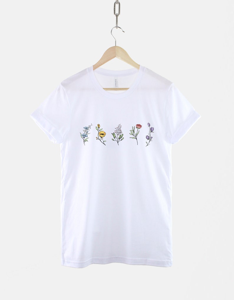 May include: White t-shirt with a line of five different coloured flowers printed on the front.