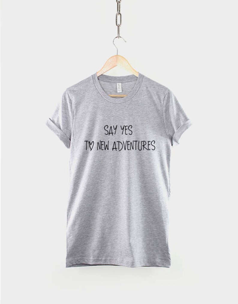 May include: Gray t-shirt with the text "Say yes to new adventures" printed on the front.