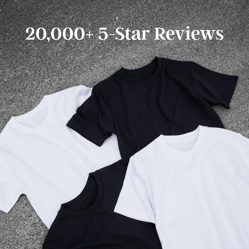 a collection of three t-shirts, one white, one black, and one solid black, laid out on a gray surface.
