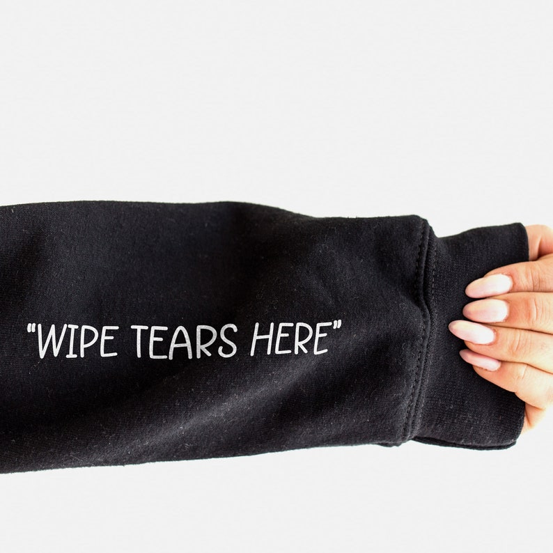 May include: Black sweatshirt with the text "WIPE TEARS HERE" printed in white on the sleeve.