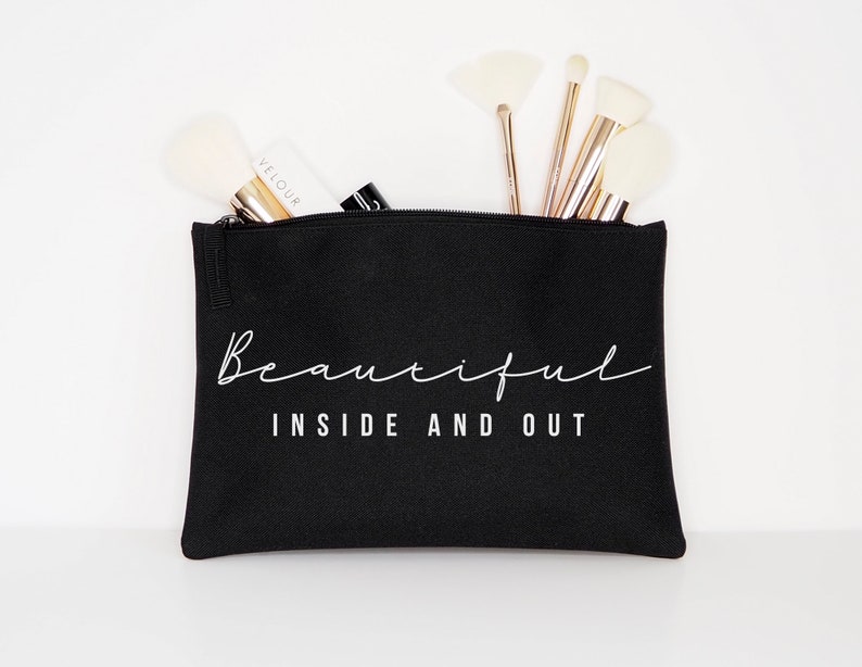 May include: Black canvas makeup bag with a zipper closure. The bag has white text that reads "Beautiful Inside and Out".
