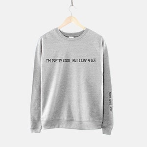 May include: Gray sweatshirt with the text "I'm pretty cool, but I cry a lot." printed on the front and "Wide tears here" printed on the right sleeve.