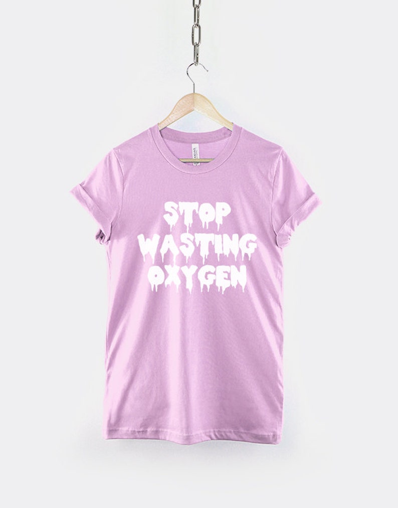 May include: A light pink t-shirt with the text "STOP WASTING OXYGEN" in white dripping letters.