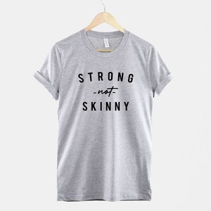 May include: A heather grey t-shirt with black text that reads "STRONG -not- SKINNY".