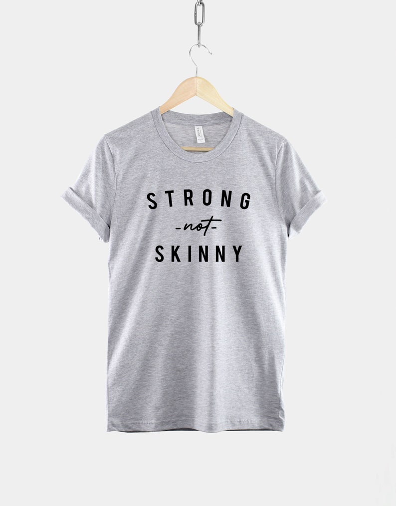 May include: A heather grey t-shirt with black text that reads "STRONG -not- SKINNY".
