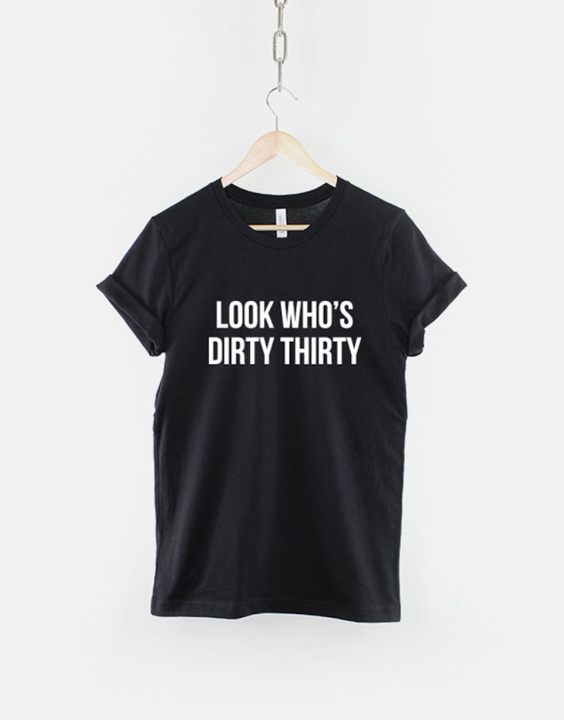 Może przedstawiać: Czarny T-shirt z białym napisem "Look Who's Dirty Thirty".