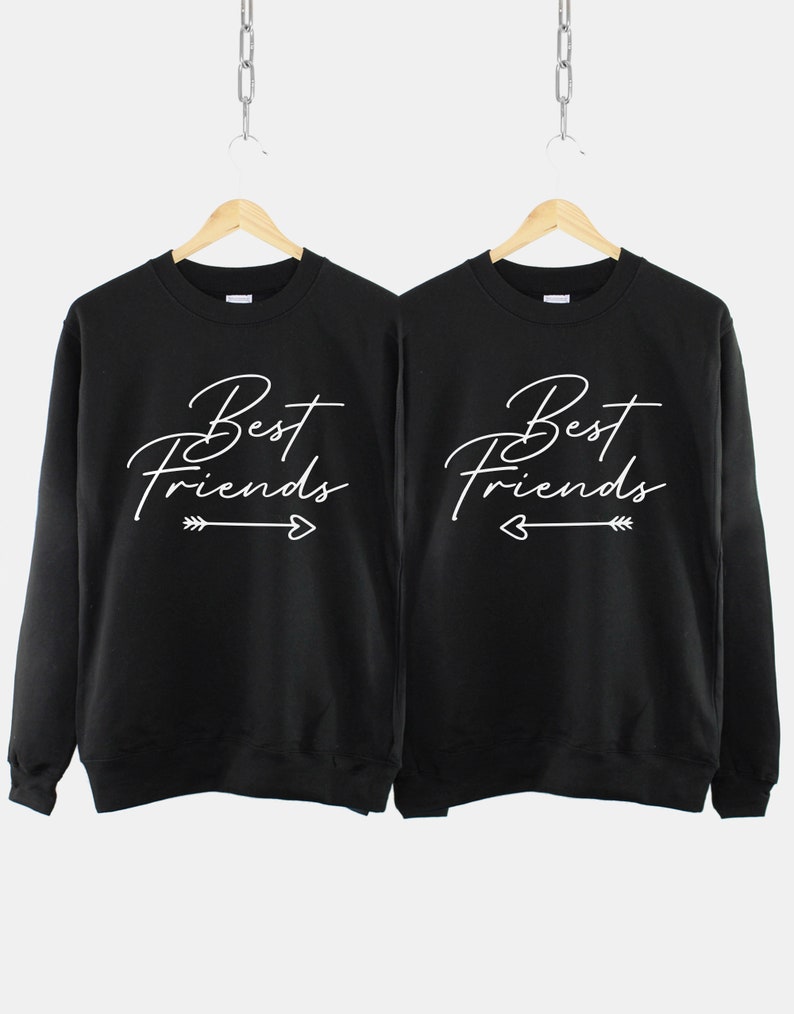 Może przedstawiać: Dwie czarne bluzy z białym napisem "Best Friends" z grafiką strzałki i serca.