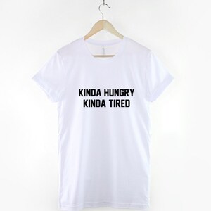 K&ouml;nnte beinhalten: Wei&szlig;es T-Shirt mit schwarzem Text, der "Kinda Hungry Kinda Tired" lautet.