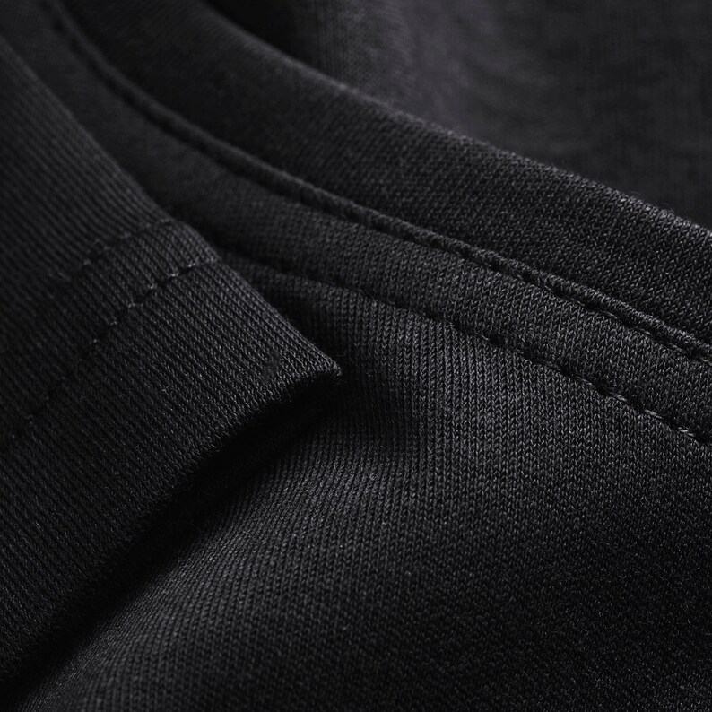 May include: Close-up of black fabric with a subtle texture and a single seam running along the edge.