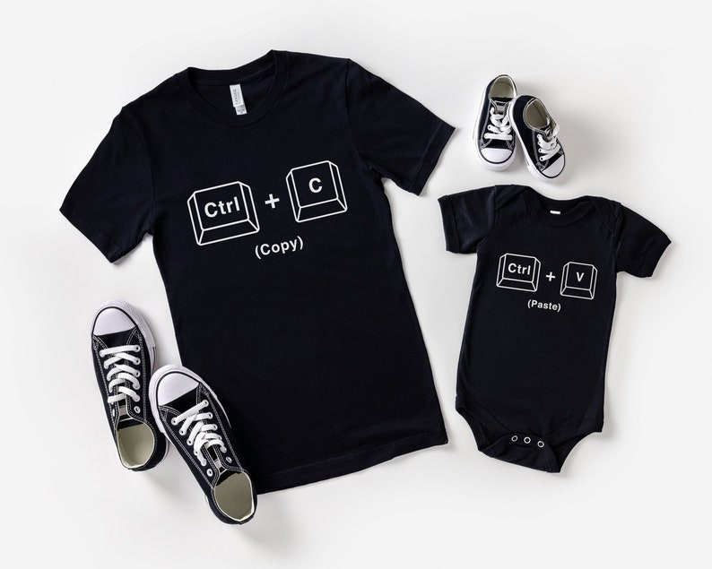 May include: Two black t-shirts with white text and images of computer keys. The larger shirt says "Ctrl + C (Copy)" and the smaller shirt says "Ctrl + V (Paste)".