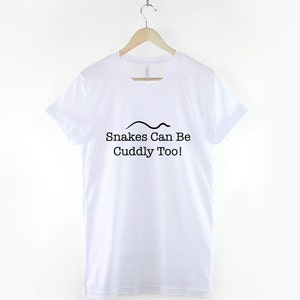 May include: White t-shirt with a black snake graphic and the text "Snakes Can Be Cuddly Too!"