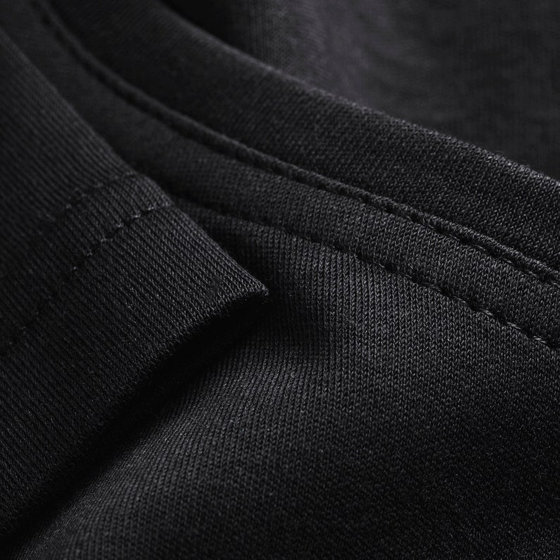 May include: Close-up of black fabric with a subtle texture and a single seam running along the edge.