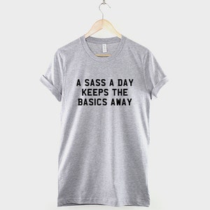 May include: A gray t-shirt with the text "A sass a day keeps the basics away" printed in black.
