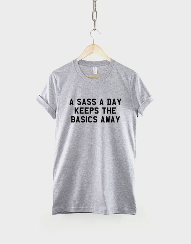 May include: A gray t-shirt with the text "A sass a day keeps the basics away" printed in black.