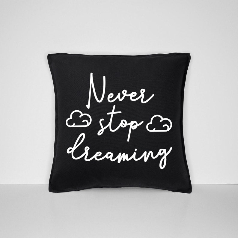 May include: Black throw pillow with white text that reads "Never stop dreaming" and two white cloud illustrations.