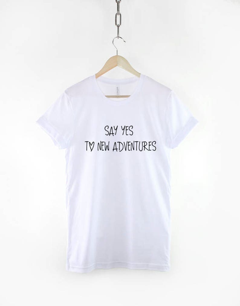 May include: White t-shirt with black text that reads "Say yes to new adventures".