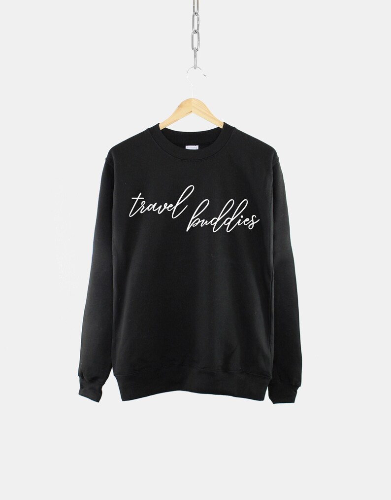 K&ouml;nnte beinhalten: Schwarzer Pullover mit wei&szlig;em Text, der in kursiver Schrift "travel buddies" lautet.