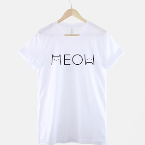 May include: White t-shirt with black text that says "MEOW" with cat ears and whiskers on either side of the word.